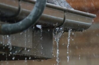 Rainwater cascading down a metal gutter