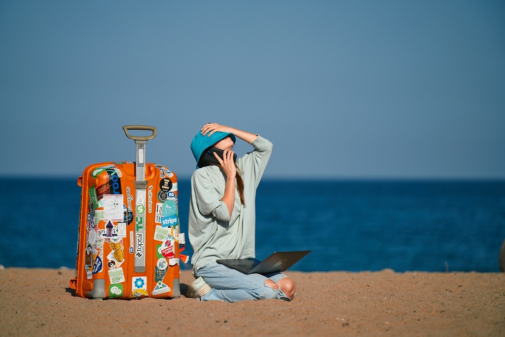 Digital nomad working abroad on the beach with luggage and a laptop