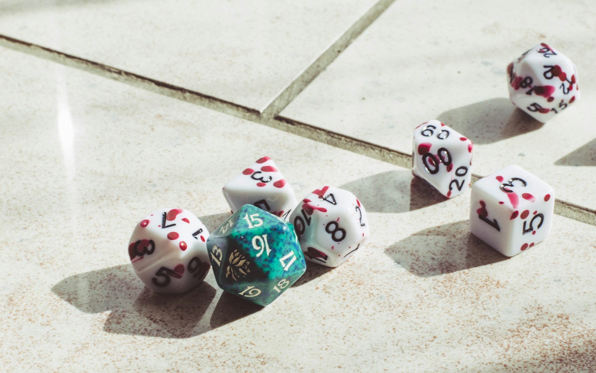 A set of seven Dungeons and Dragons dice on a white tiled floor.