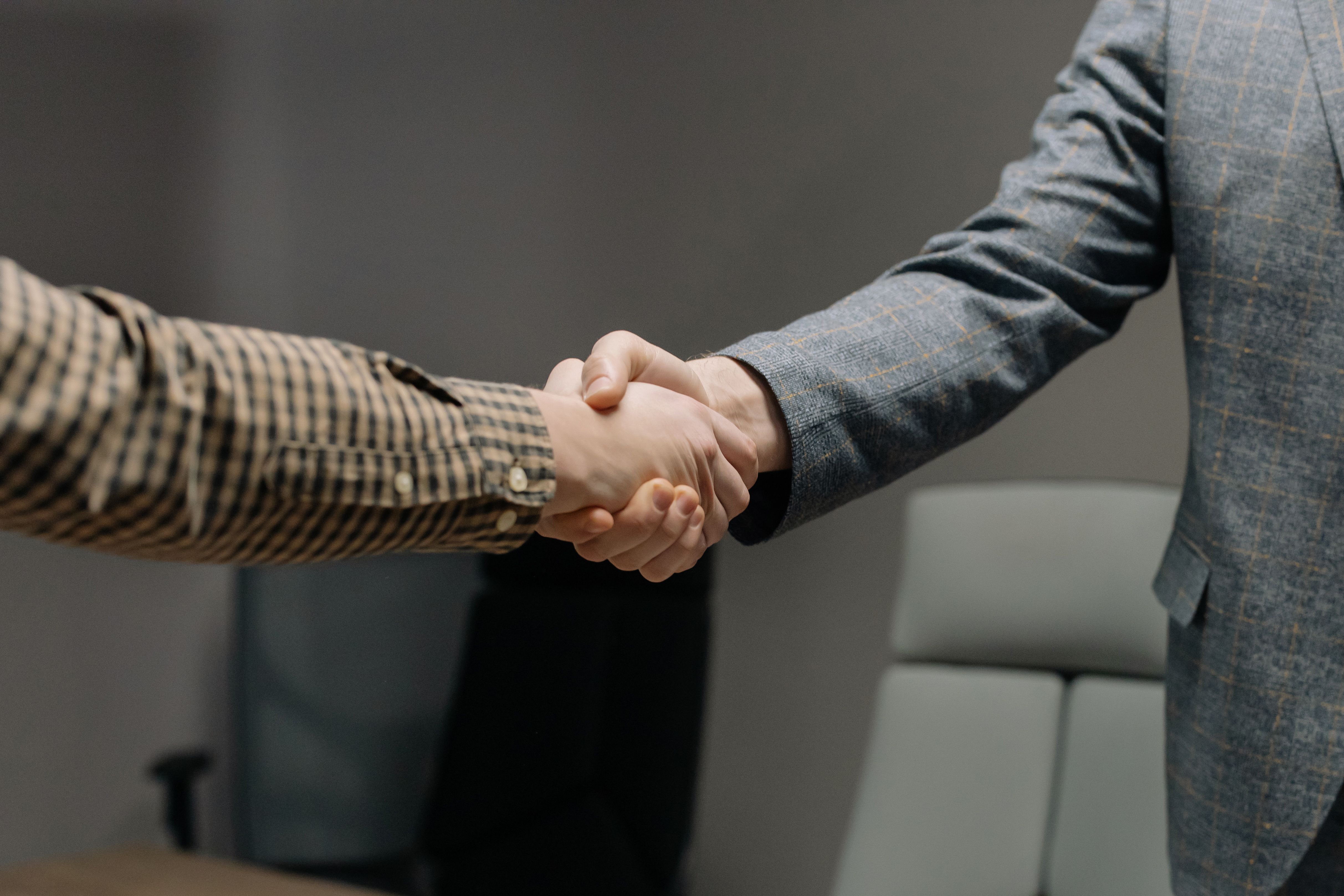 Close-up of two professionals shaking hands in an office, symbolizing the trust built through a clean, professional brand