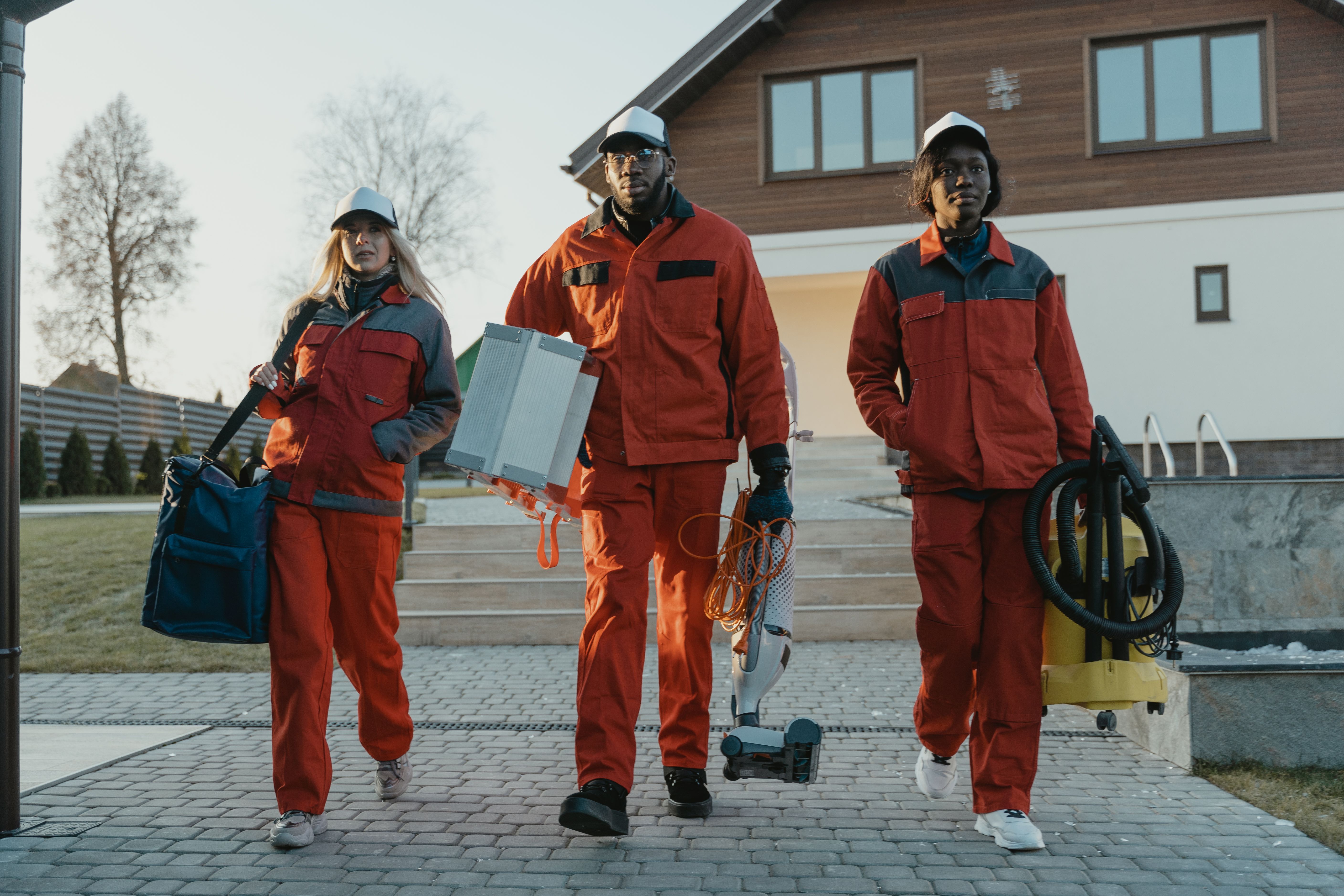 Diverse team of professional cleaners walking in uniform and holding cleaning tools