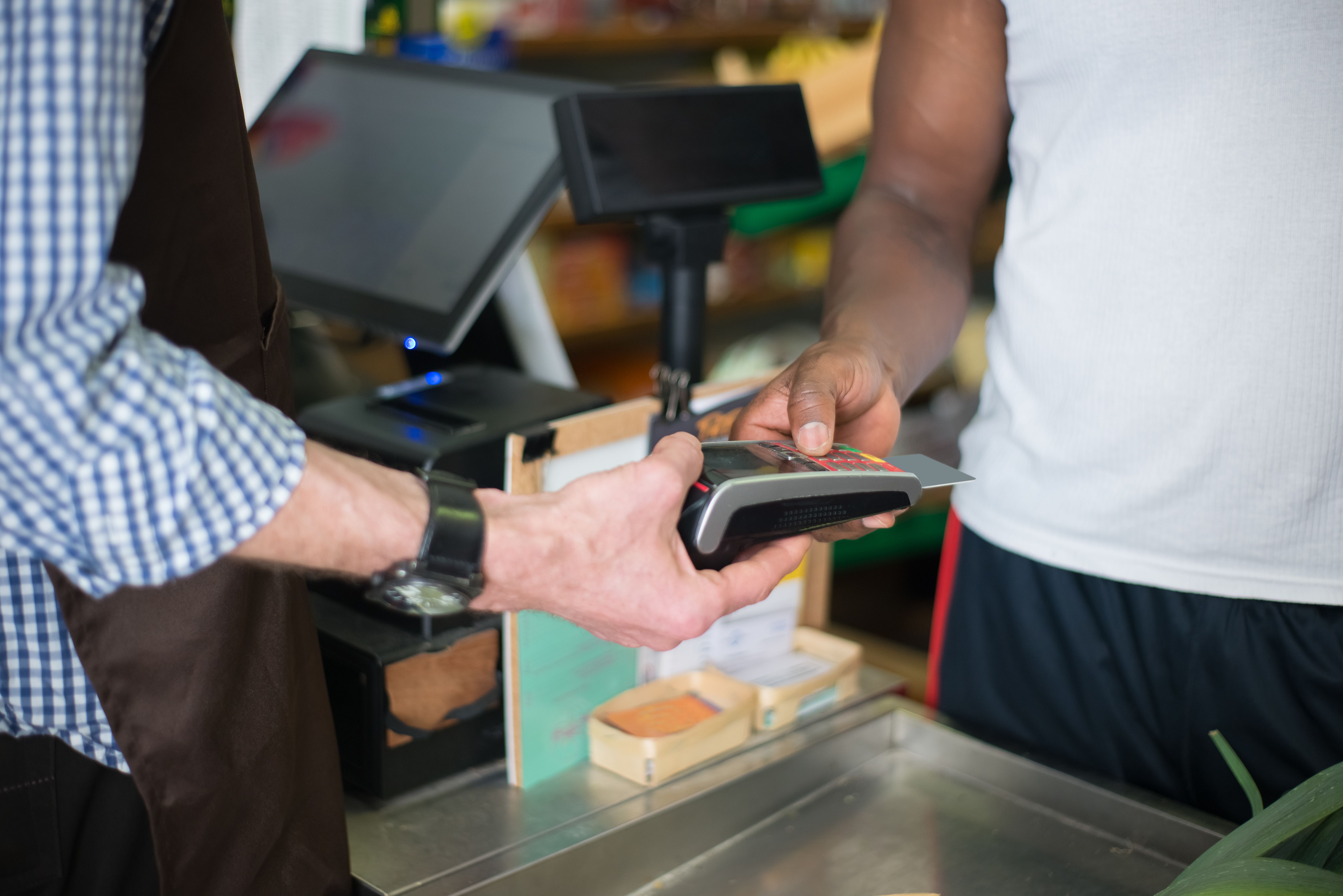 Customer making a card payment at a store checkout counter using a point-of-sale card reader