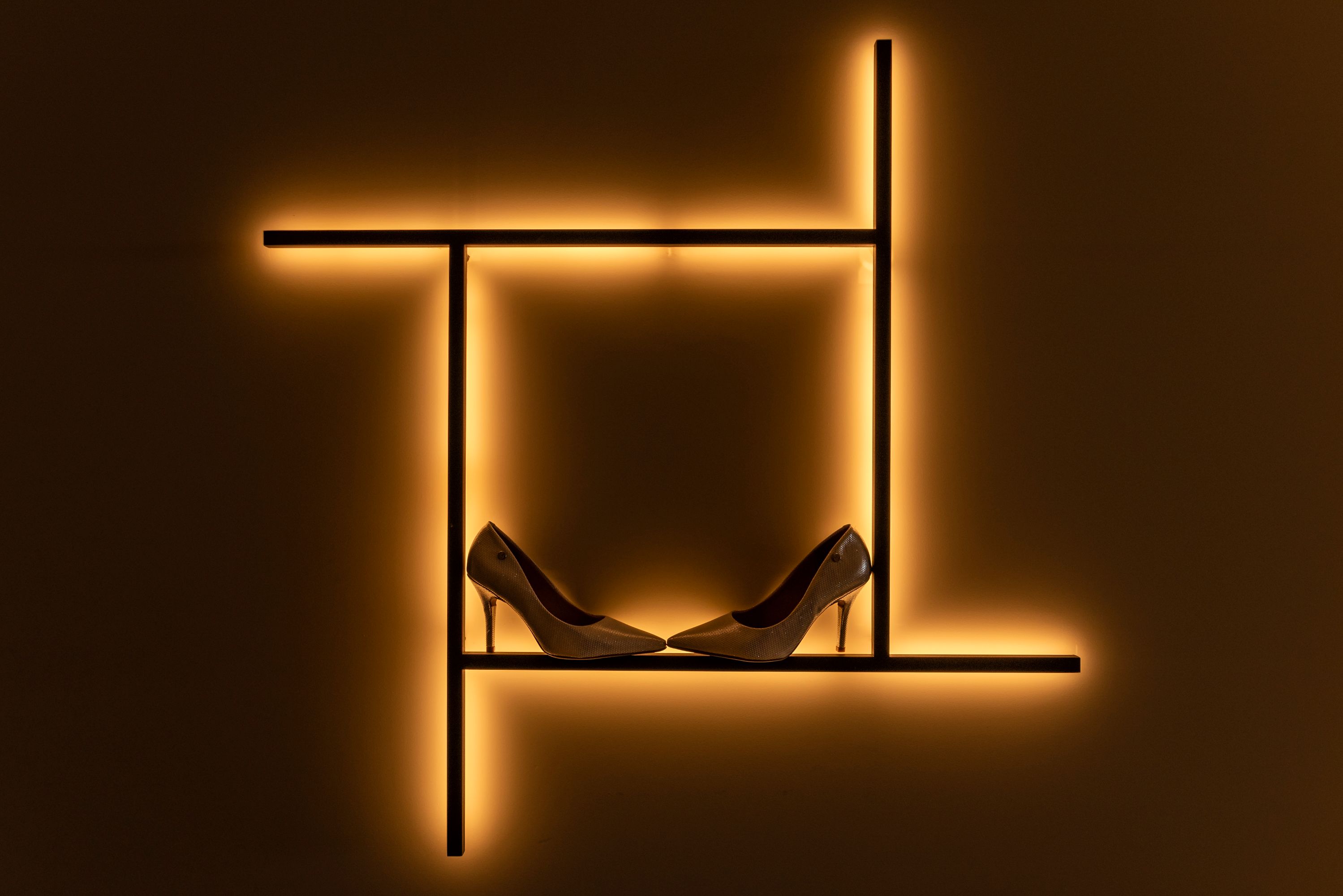 High heels elegantly displayed on illuminated shelves against a warm background