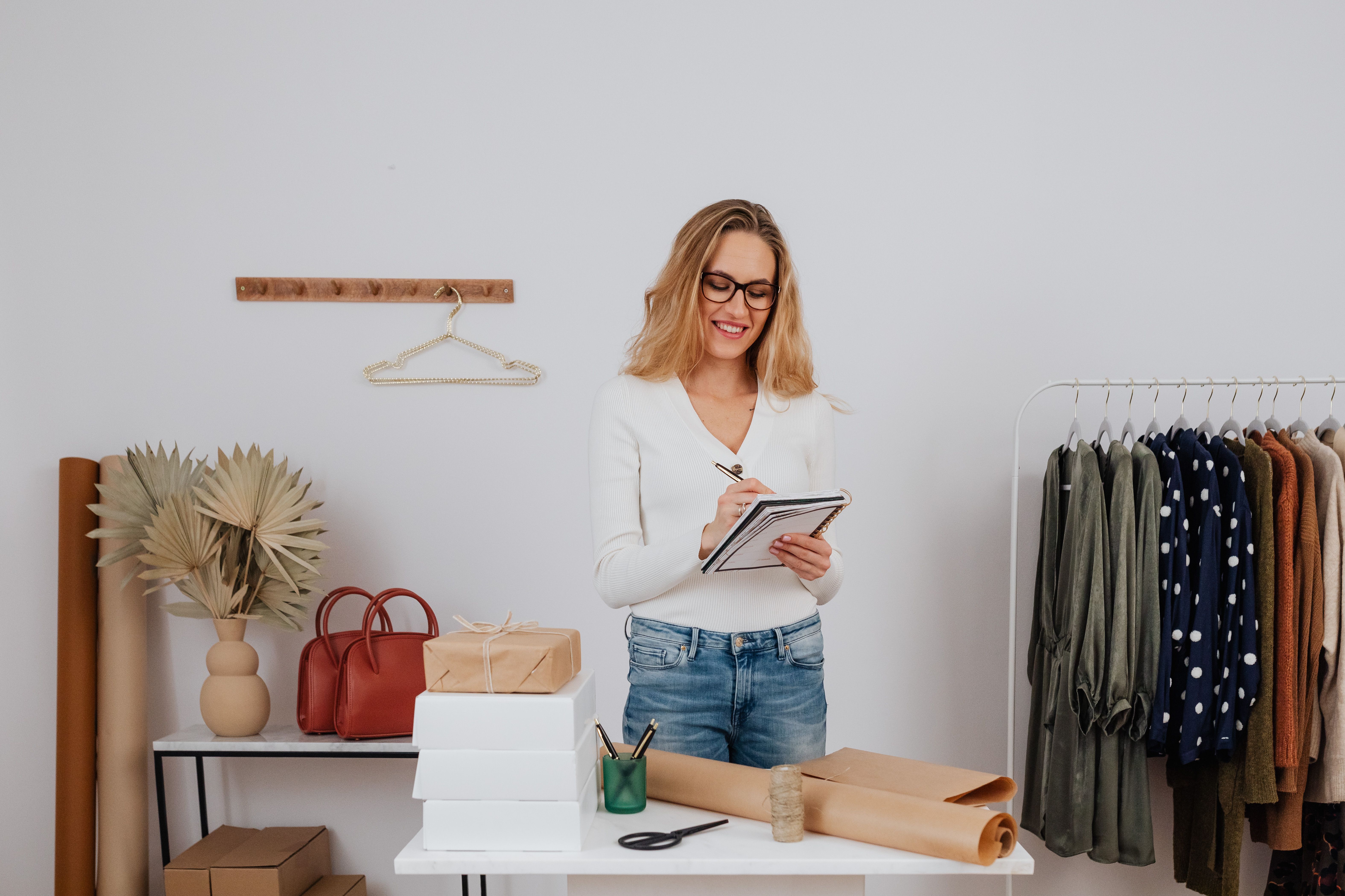 Small business owner arranging merchandise in a chic boutique with clothing rack and gifts